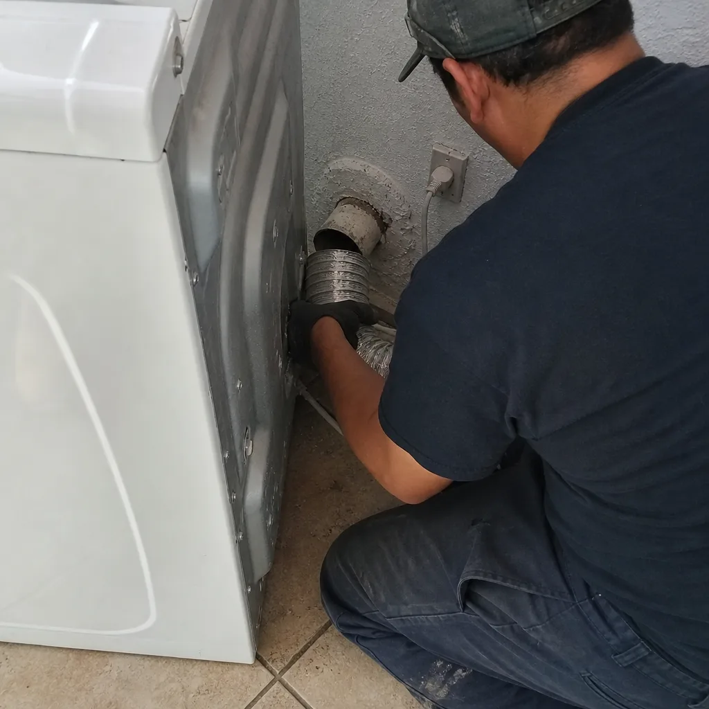 Technician connecting a metal dryer vent hose to a dryer unit